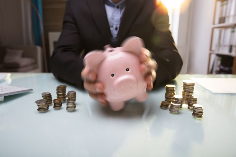 Businessperson's Hand Shaking Piggy Bank - Blog Ciclo Contabilidade